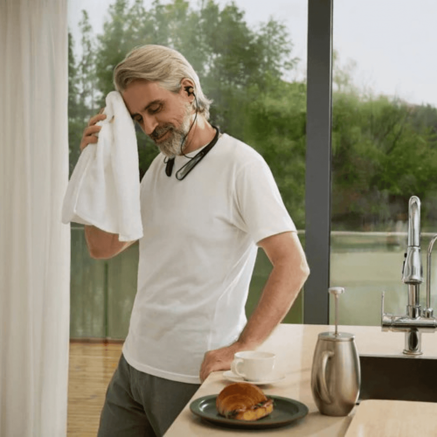 Man drying off sweat after wearing IP-54 water and dustproof Incus hearing device while exercising