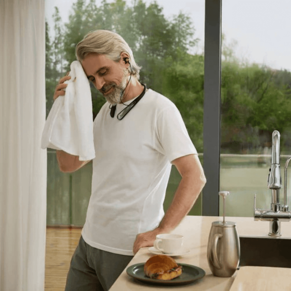 Man drying off sweat after wearing IP-54 water and dustproof Incus hearing aid while exercising
